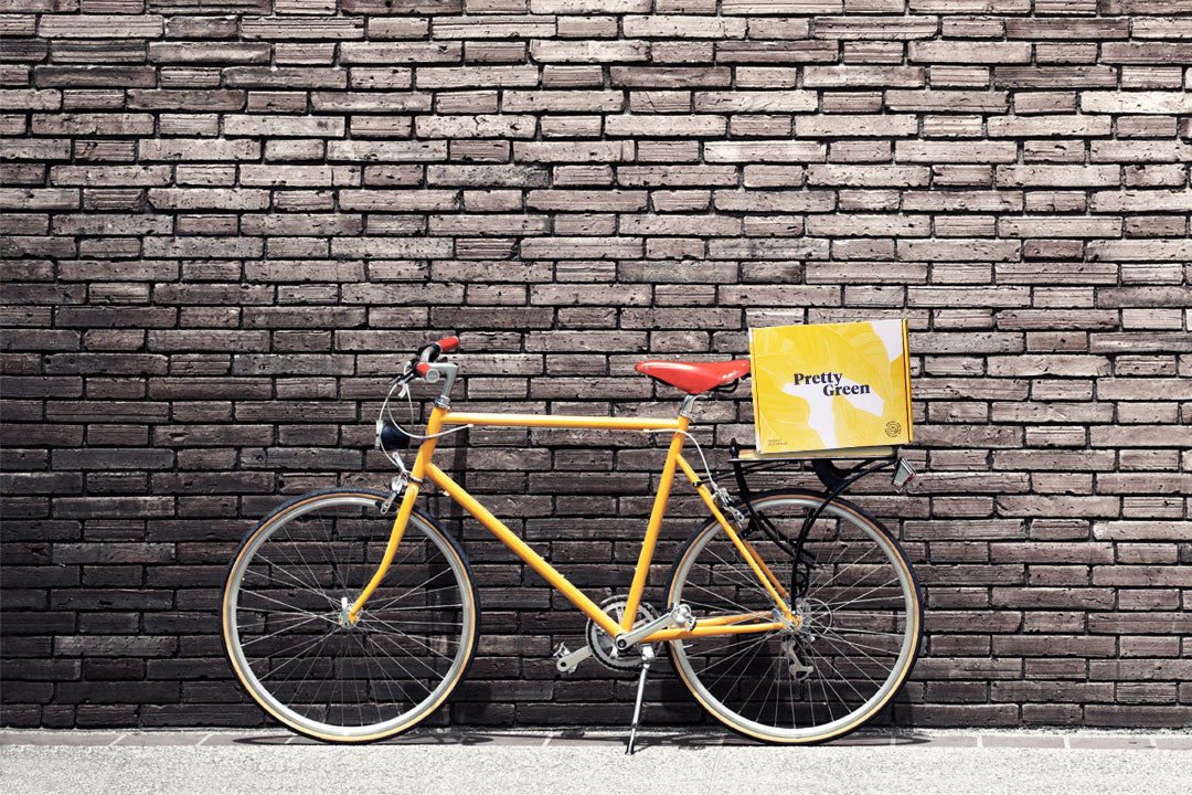 Yellow bike parked against a brick wall with yellow Pretty Green gift box